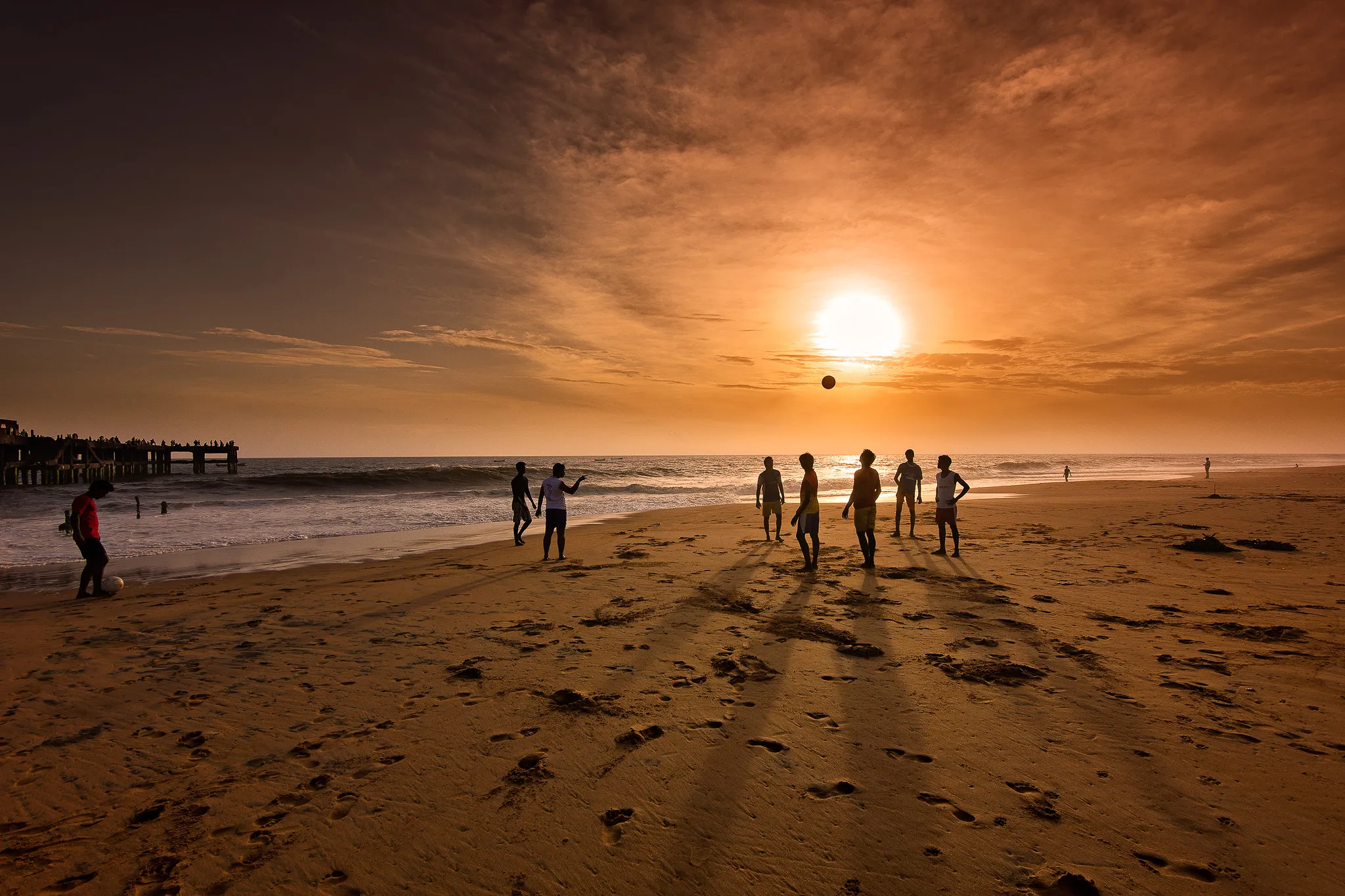 Kids playing football on Shankumugham Beach at sunset, Kerala