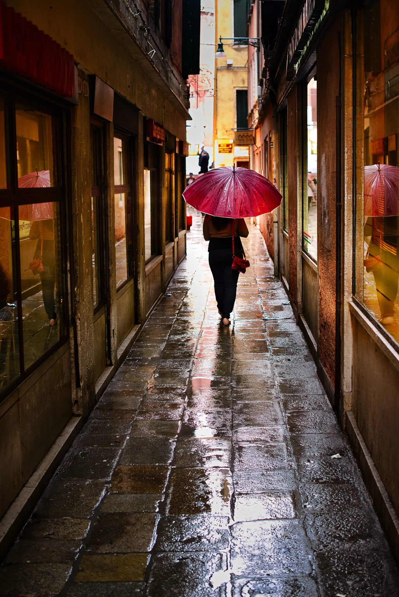 Reflections of lights and colour in rain-soaked cobblestones in Venice at night
